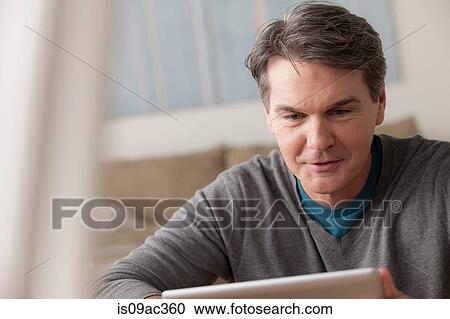 Mature man using digital tablet View Large Photo Image Stock Image - Mature man using digital tablet. Fotosearch
