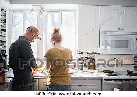 Mid adult couple preparing food in kitchen View Large Photo Image Stock Image - Mid adult couple preparing food in kitchen. Fotosearch