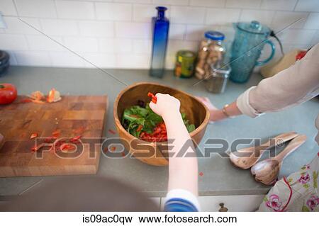 Stock Photo - Mother and son preparing salad on kitchen counter. Fotosearch
