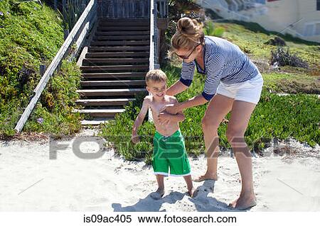 Stock Photography - Mother applying sun cream to toddler at beach. Fotosearch