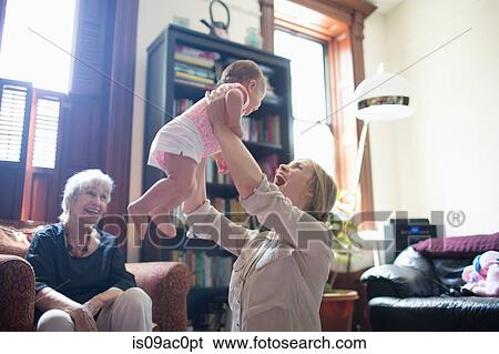 Mother lifting daughter with grandmother watching View Large Photo Image Stock Photograph - Mother lifting daughter with grandmother watching. Fotosearch