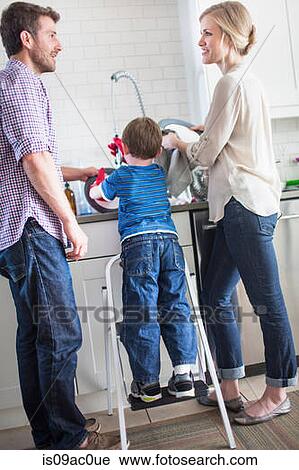 Stock Image - Parents and son washing dishes. Fotosearch