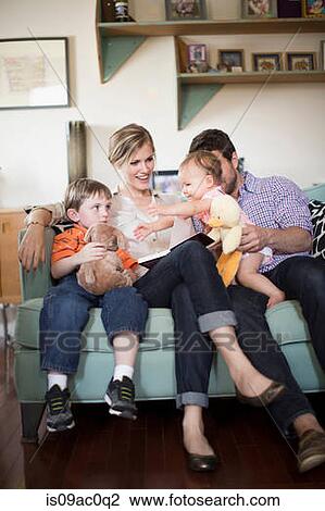 Parents with two children sitting on sofa View Large Photo Image Stock Image - Parents with two children sitting on sofa. Fotosearch