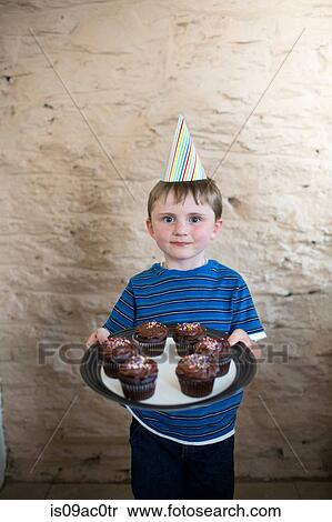 Portrait of boy wearing party hat holding cupcakes View Large Photo Image Stock Photography - Portrait of boy wearing party hat holding cupcakes. Fotosearch