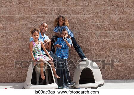 Stock Photograph - Portrait of four siblings and dog in kennel. Fotosearch