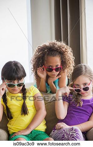 Stock Photo - Portrait of three girls wearing sunglasses. Fotosearch