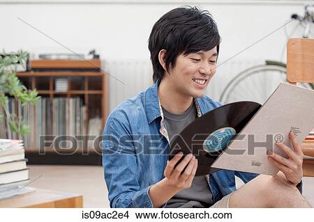 Picture - Portrait of young man holding vinyl record. Fotosearch