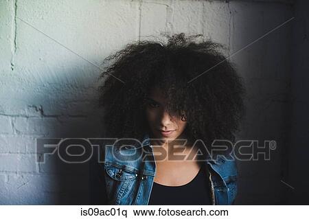 Stock Photography - Portrait of young woman leaning against wall. Fotosearch
