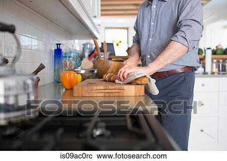 Stock Image - Senior man preparing food at home. Fotosearch