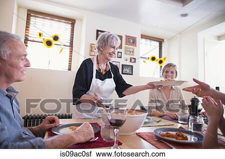 Senior woman serving food at family dinner View Large Photo Image Stock Image - Senior woman serving food at family dinner. Fotosearch