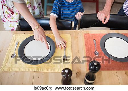 Stock Photography - Son setting the table, mother pointing. Fotosearch