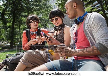 Stock Image - Three friends in park with mp3 player. Fotosearch