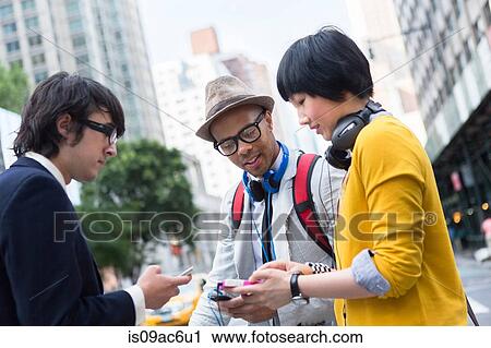 Stock Image - Three friends on street with mp3 player. Fotosearch
