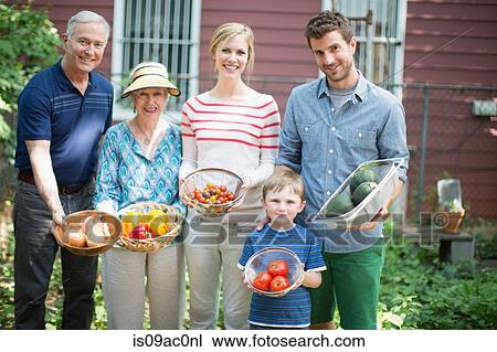 Stock Image - Three generation family with homegrown vegetables. Fotosearch