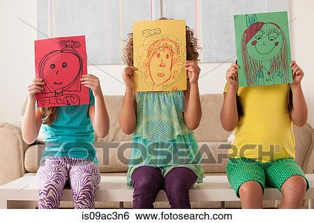 Three girls holding pictures over faces View Large Photo Image Stock Photograph - Three girls holding pictures over faces. Fotosearch