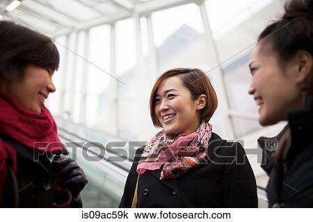Stock Image - Three young Asian women talking. Fotosearch