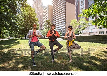 Stock Photograph - Three young people doing yoga in park. Fotosearch