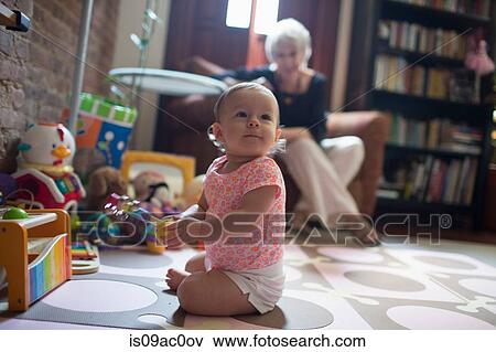 Stock Photo - Toddler girl sitting on floor playing. Fotosearch