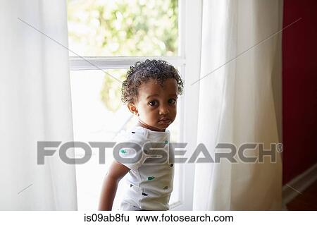 Toddler standing beside window View Large Photo Image Stock Photograph - Toddler standing beside window. Fotosearch