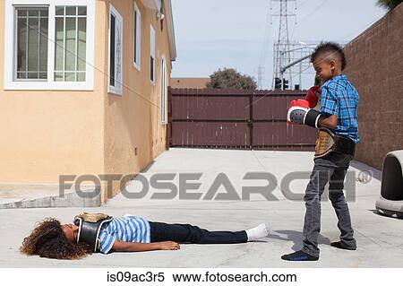 Two boys in yard, one wearing boxing gloves the other lying on back View Large Photo Image Stock Photography - Two boys in yard, one wearing boxing gloves the other lying on back. Fotosearch