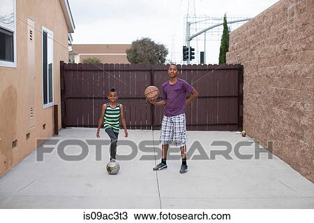 Two boys in yard with basketball and football View Large Photo Image Stock Image - Two boys in yard with basketball and football. Fotosearch