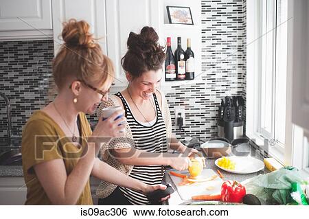 Stock Photograph - Two women preparing food in kitchen. Fotosearch