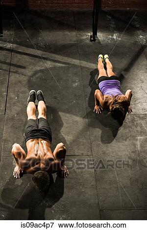 Stock Photo - Two young adults doing push ups in gym. Fotosearch
