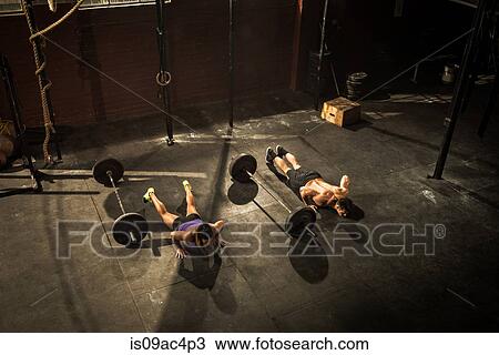 Stock Image - Two young adults in gym doing push ups. Fotosearch