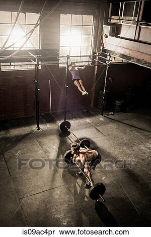 Stock Photography - Two young adults working out in gym. Fotosearch