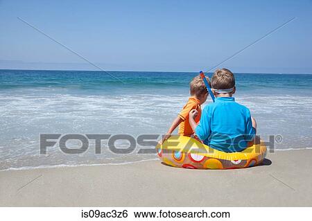Two young brothers sitting on rubber ring at beach View Large Photo Image Stock Photograph - Two young brothers sitting on rubber ring at beach. Fotosearch