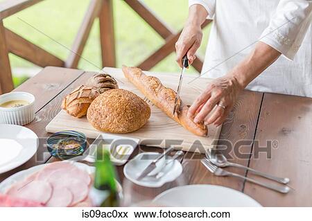 Woman cutting baguette View Large Photo Image Stock Photo - Woman cutting baguette. Fotosearch