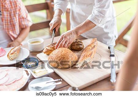 Stock Photography - Woman cutting baguette. Fotosearch