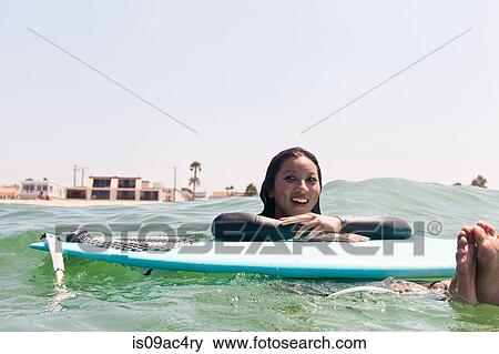 Stock Photo - Woman floating with surfboard, Hermosa Beach, California, USA. Fotosearch