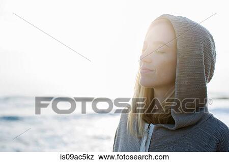 Stock Photo - Woman in hoodie at beach. Fotosearch