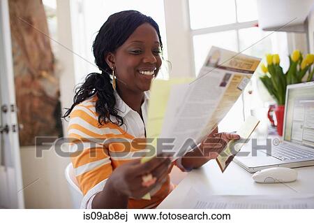 Stock Image - Woman looking at paperwork. Fotosearch