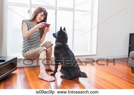 Stock Photography - Woman photographing dog on camera phone. Fotosearch
