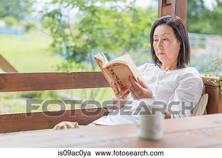 Woman reading book on patio View Large Photo Image Stock Image - Woman reading book on patio. Fotosearch