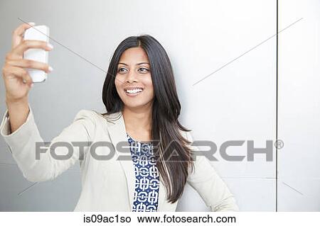 Picture - Woman taking self portrait using smartphone. Fotosearch