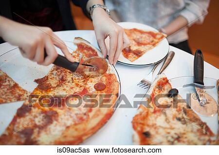 Woman using pizza cutter to cut pizza, close up View Large Photo Image Stock Photograph - Woman using pizza cutter to cut pizza, close up. Fotosearch