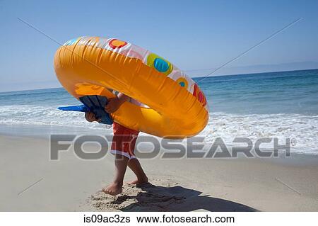 Young boy carrying rubber ring on beach View Large Photo Image Stock Photograph - Young boy carrying rubber ring on beach. Fotosearch