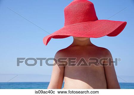 Stock Image - Young boy hidden by large red sunhat. Fotosearch
