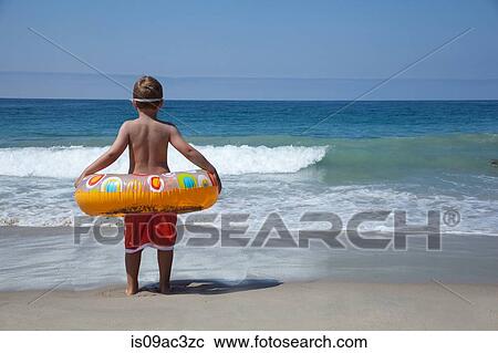 Young boy playing with rubber ring at beach View Large Photo Image Stock Image - Young boy playing with rubber ring at beach. Fotosearch