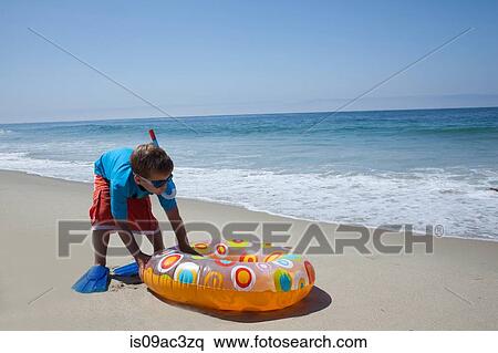 Young boy pushing rubber ring on beach View Large Photo Image Stock Photography - Young boy pushing rubber ring on beach. Fotosearch