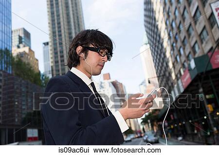 Stock Image - Young businessman using mp3 player. Fotosearch