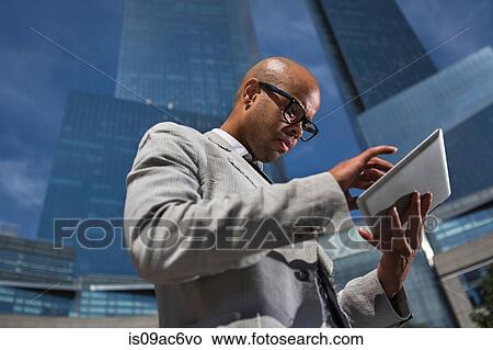 Picture - Young businessman using table outside office buildings. Fotosearch