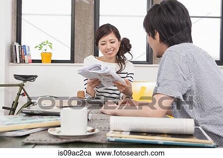 Stock Image - Young couple in apartment planning at table. Fotosearch