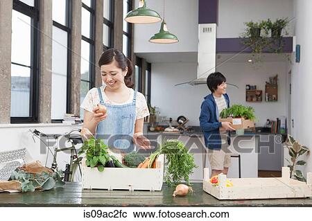 Stock Image - Young couple in kitchen preparing food. Fotosearch