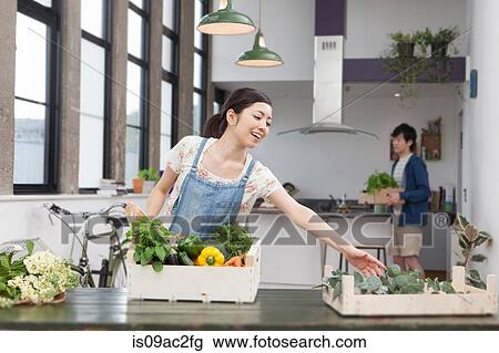 Stock Image - Young couple in kitchen preparing fresh food. Fotosearch