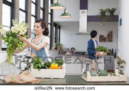 Stock Image - Young couple in kitchen preparing meal. Fotosearch