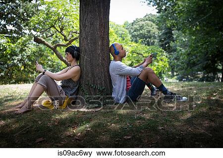 Young couple leaning against tree trunk View Large Photo Image Stock Photo - Young couple leaning against tree trunk. Fotosearch